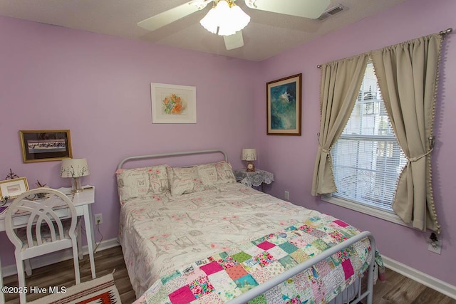 bedroom featuring a ceiling fan, baseboards, visible vents, and wood finished floors