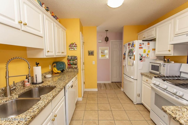 kitchen featuring white appliances, light tile patterned floors, white cabinets, a textured ceiling, and a sink