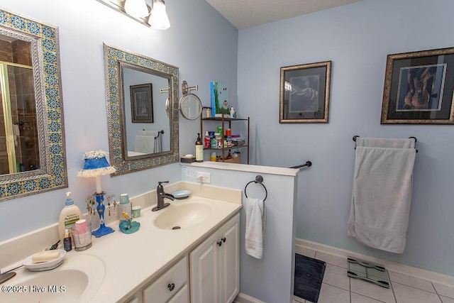 full bath featuring double vanity, baseboards, tile patterned floors, a shower stall, and a sink