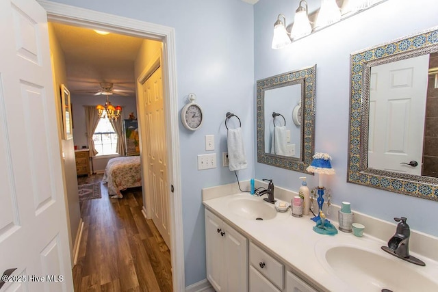 ensuite bathroom featuring double vanity, ensuite bathroom, a sink, and wood finished floors