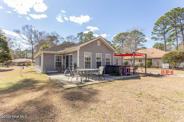 rear view of house featuring a patio, a yard, and a hot tub