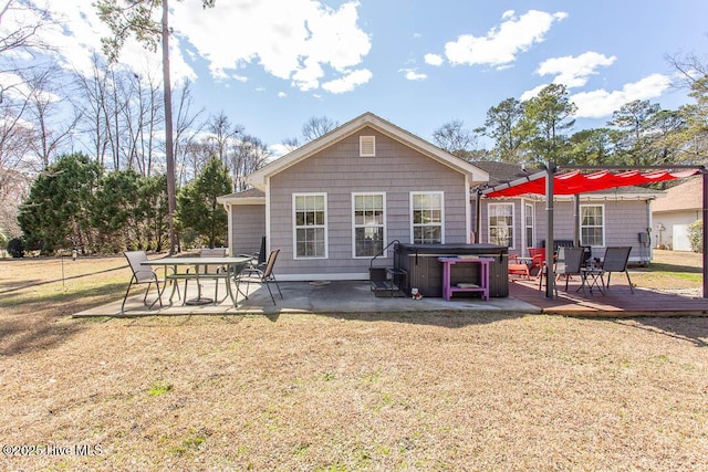 rear view of property featuring a patio area, a hot tub, a deck, and a lawn