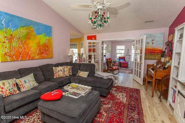 living area featuring french doors, visible vents, vaulted ceiling, and light wood-style flooring