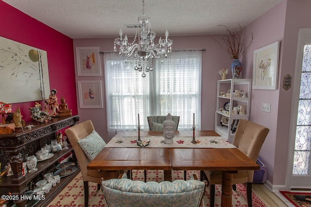 dining space featuring a chandelier, a textured ceiling, plenty of natural light, and wood finished floors