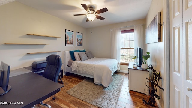 bedroom featuring wood finished floors, a ceiling fan, and baseboards