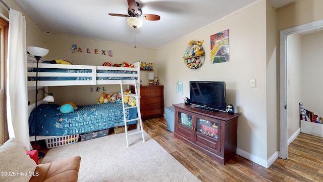 bedroom featuring a ceiling fan, baseboards, and wood finished floors