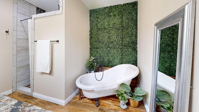 full bathroom featuring baseboards, a tile shower, a freestanding bath, and wood finished floors