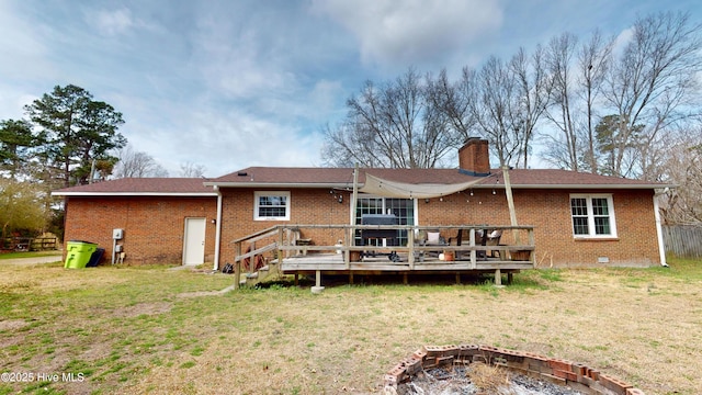 back of property featuring an outdoor fire pit, brick siding, a yard, a wooden deck, and a chimney