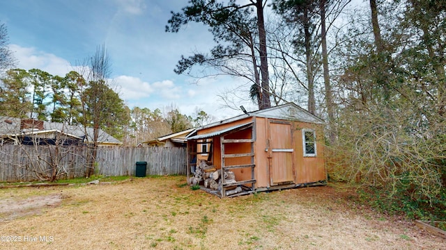 view of outbuilding featuring fence and an outdoor structure