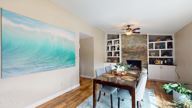 dining area with built in shelves, ceiling fan, baseboards, and wood finished floors