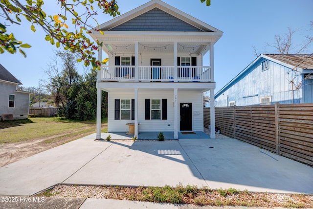 view of front facade with a patio area, a balcony, a front lawn, and a fenced backyard