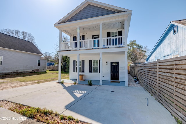 rear view of house featuring a patio area, a balcony, a lawn, and fence