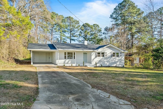 single story home with concrete driveway, a carport, a chimney, and a front yard