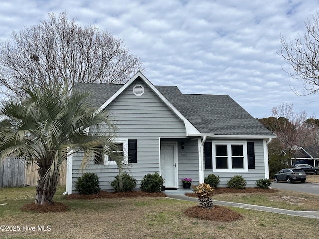 view of front facade with a front yard and roof with shingles