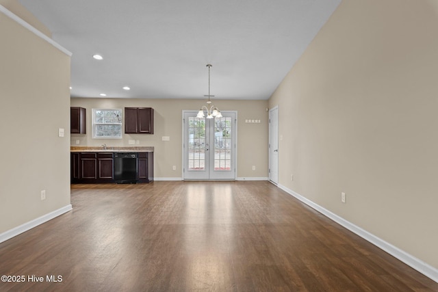 unfurnished living room with a notable chandelier, recessed lighting, baseboards, and dark wood-style flooring