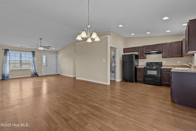 kitchen featuring under cabinet range hood, light countertops, vaulted ceiling, wood finished floors, and black appliances