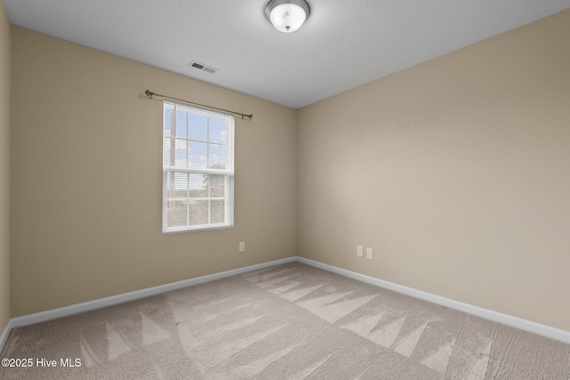 empty room featuring light colored carpet, visible vents, and baseboards