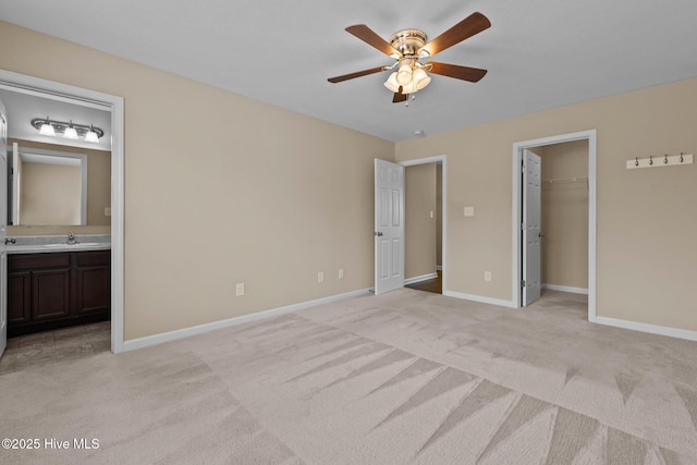 unfurnished bedroom featuring a sink, light colored carpet, baseboards, and connected bathroom