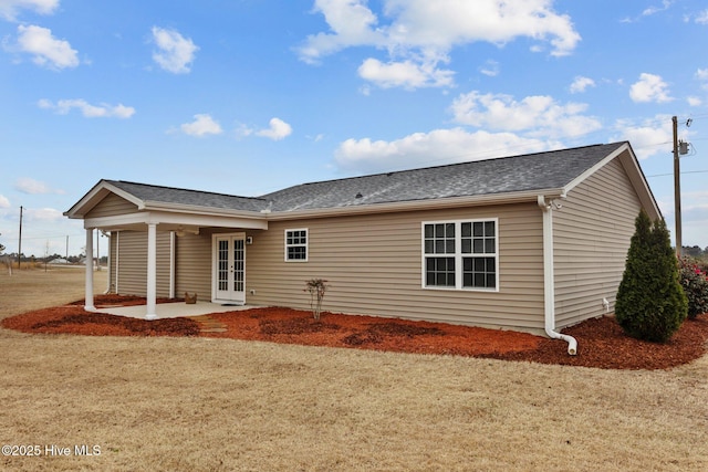 back of property with a patio area, french doors, a lawn, and a shingled roof