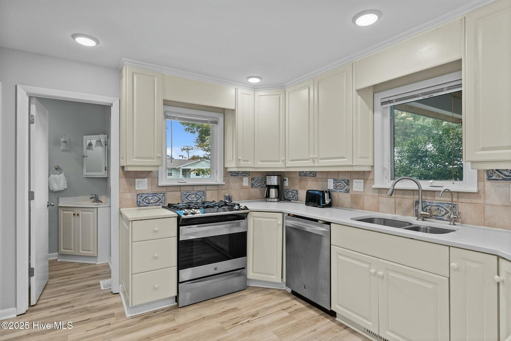 kitchen featuring stainless steel appliances, light countertops, a sink, and light wood finished floors