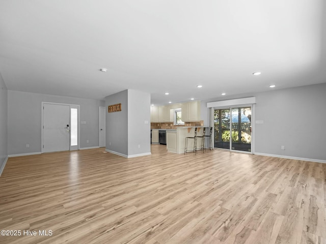 unfurnished living room with baseboards and light wood-type flooring