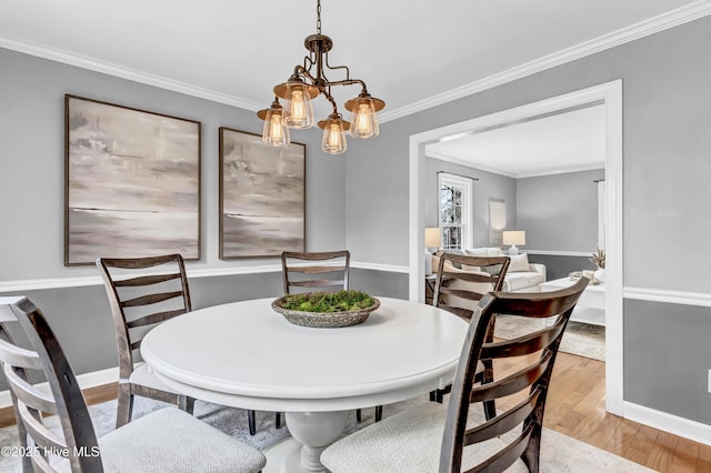 dining room with ornamental molding, an inviting chandelier, wood finished floors, and baseboards