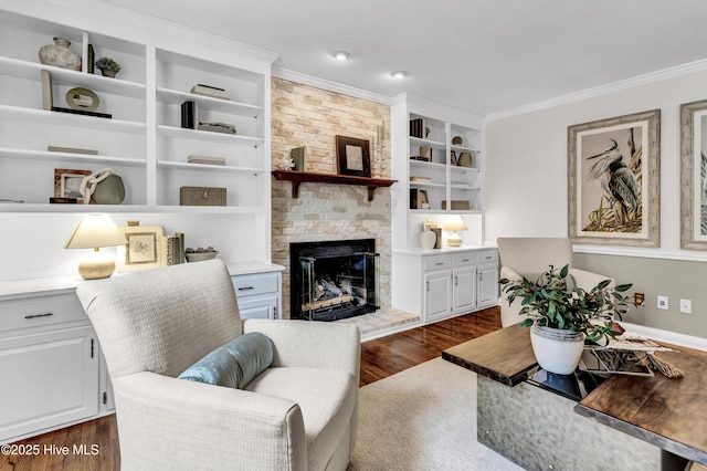 living area featuring dark wood-style floors, a fireplace, built in shelves, and crown molding