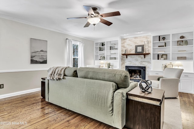 living room with light wood finished floors, baseboards, ceiling fan, crown molding, and a fireplace