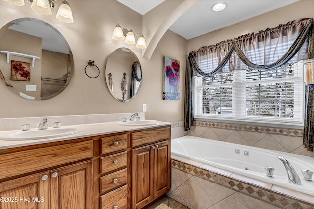 full bathroom with double vanity, a garden tub, and a sink