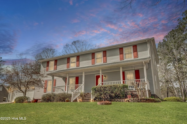 view of front of property featuring covered porch, a front lawn, and a garage