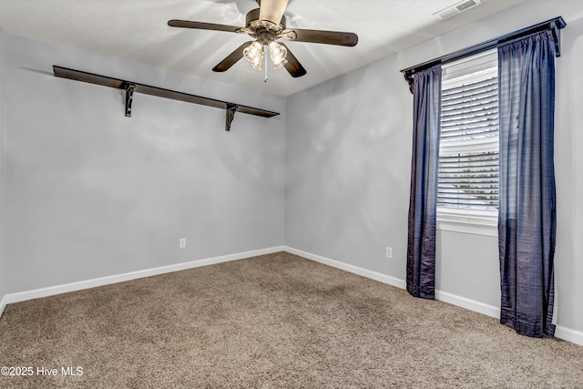 unfurnished room with a textured ceiling, carpet flooring, visible vents, baseboards, and a ceiling fan