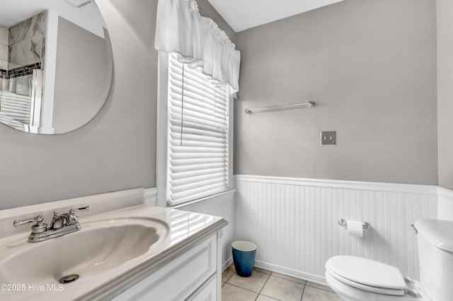 bathroom featuring toilet, tile patterned flooring, vanity, and wainscoting