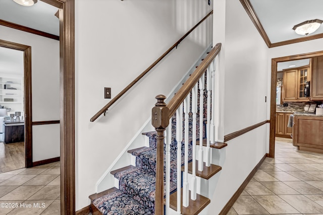 stairway with baseboards, crown molding, and tile patterned floors