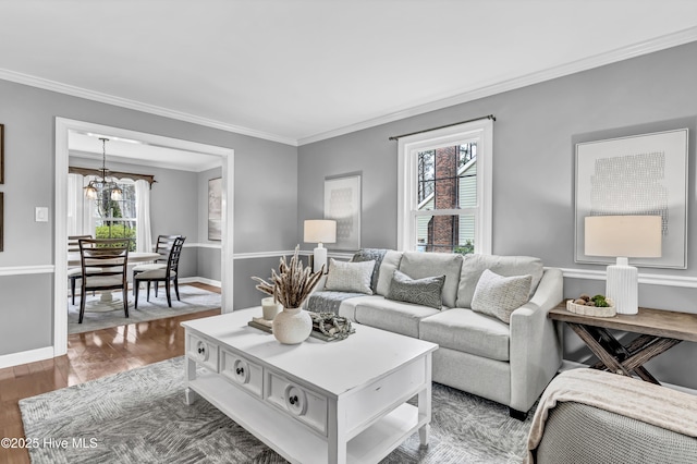 living room with ornamental molding, baseboards, an inviting chandelier, and wood finished floors