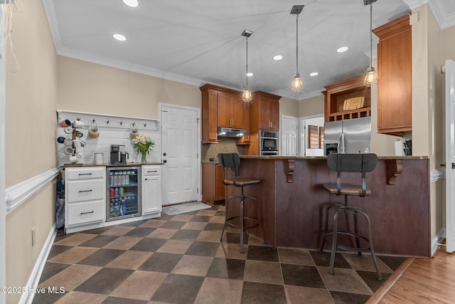 kitchen with appliances with stainless steel finishes, wine cooler, ornamental molding, and under cabinet range hood