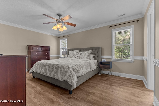 bedroom with ornamental molding, multiple windows, and wood finished floors