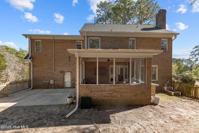 rear view of property featuring brick siding, a patio, a chimney, and fence