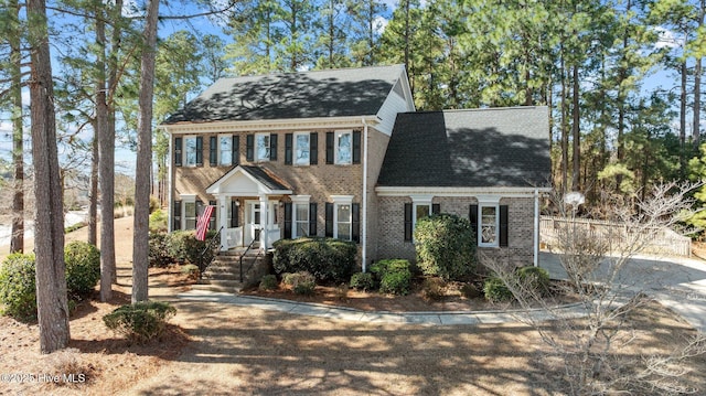 colonial inspired home featuring brick siding and roof with shingles