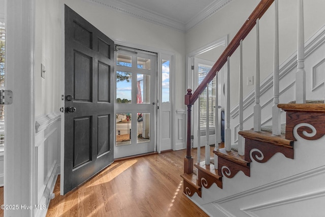 foyer entrance featuring stairs, light wood-type flooring, and crown molding