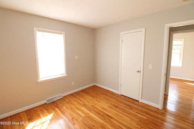 spare room featuring baseboards, visible vents, and light wood finished floors