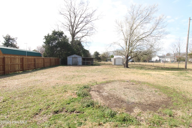 view of yard featuring a storage shed, fence, and an outbuilding