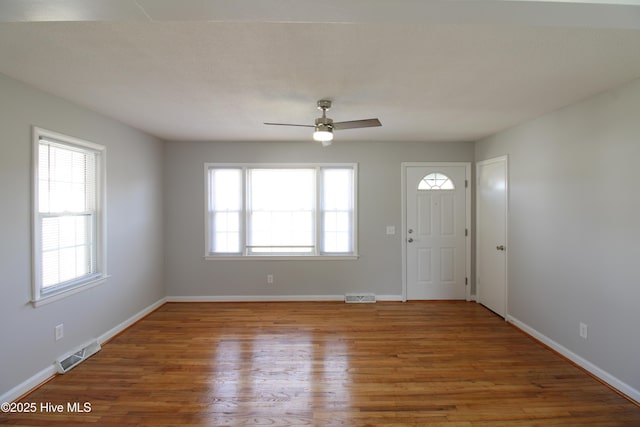 foyer entrance with baseboards, visible vents, and wood finished floors