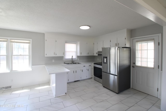 kitchen featuring stainless steel appliances, light countertops, visible vents, a sink, and a peninsula