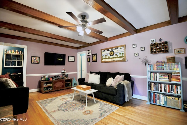 living area with beamed ceiling, wood finished floors, a ceiling fan, and baseboards