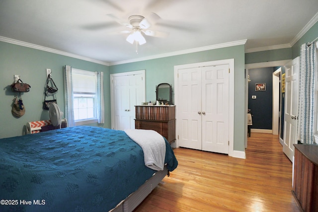 bedroom with baseboards, ceiling fan, ornamental molding, light wood-type flooring, and two closets