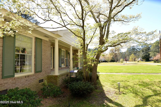 view of home's exterior with a yard, a porch, and brick siding