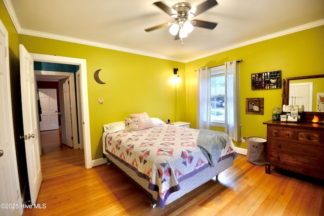 bedroom with baseboards, light wood finished floors, and crown molding