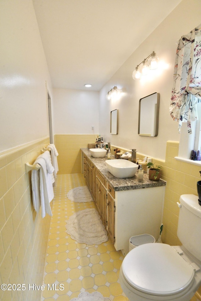 bathroom with toilet, a sink, and wainscoting