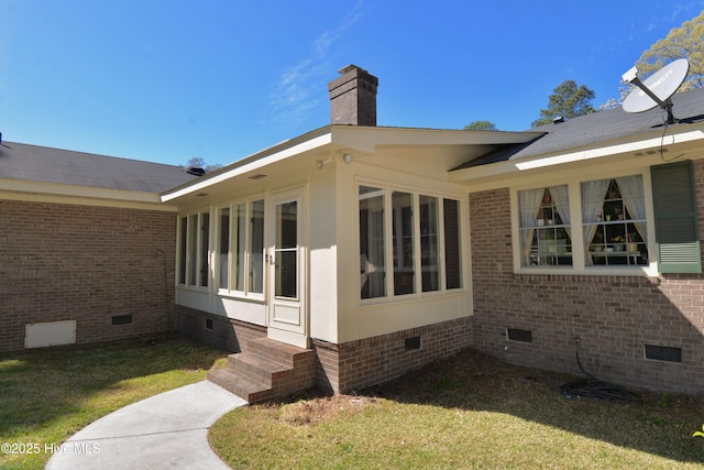 view of property exterior featuring crawl space, entry steps, a chimney, and brick siding