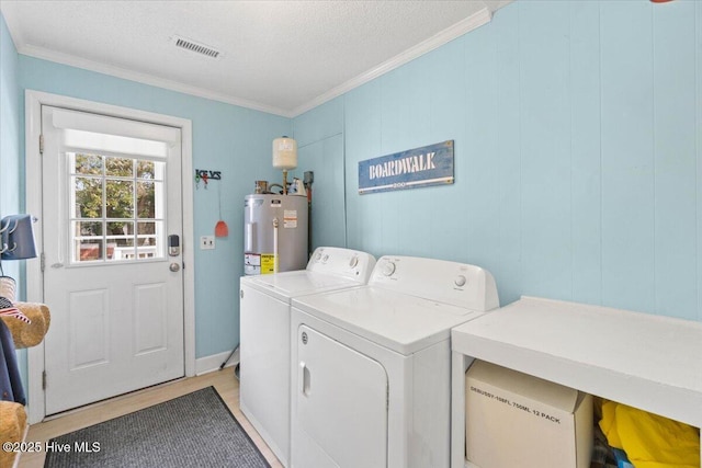 laundry area featuring laundry area, visible vents, ornamental molding, washing machine and clothes dryer, and water heater